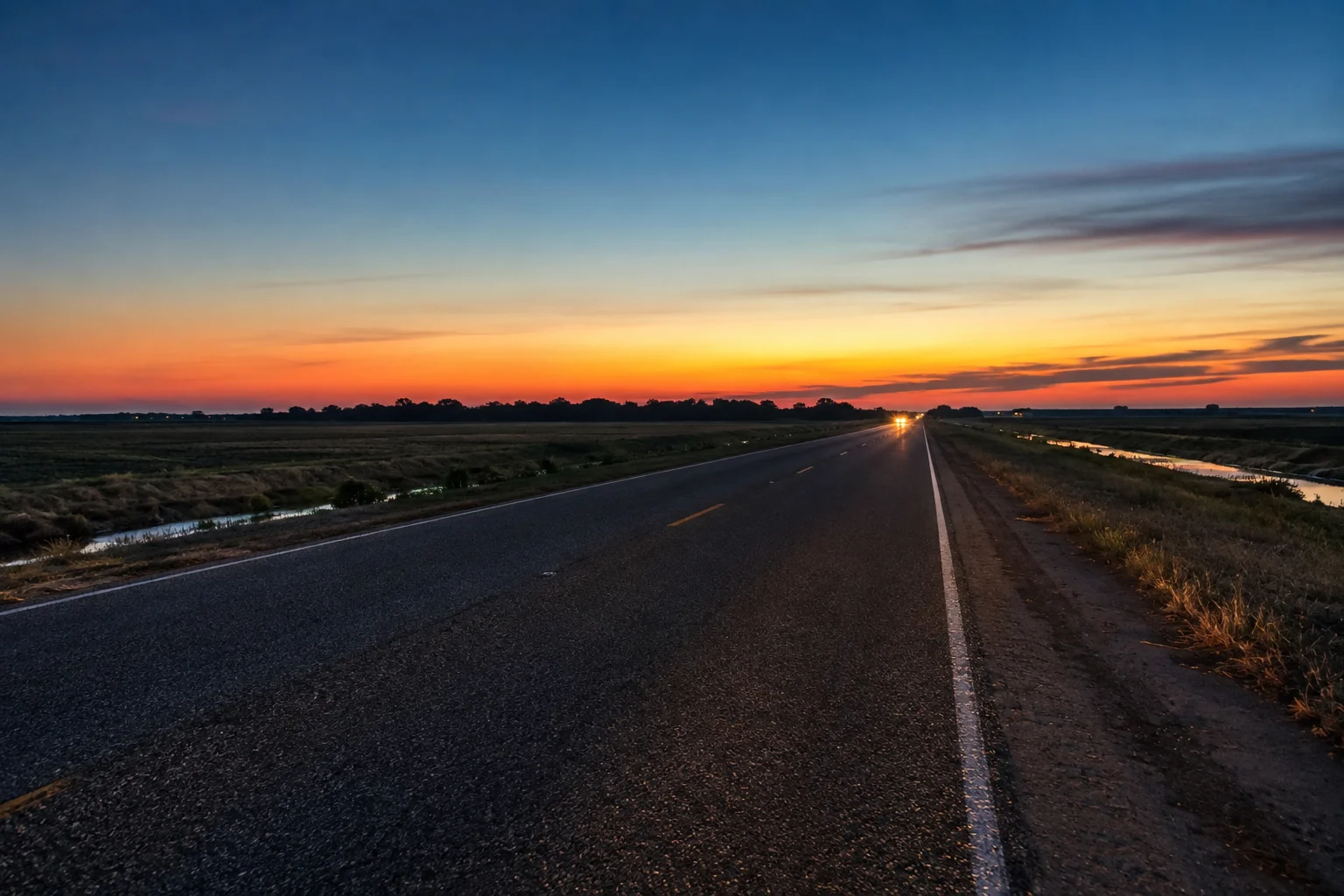 Unlit two-lane rural farm road in South Texas at dusk with no centre barrier, the road type behind Willacy County's high fatality rate