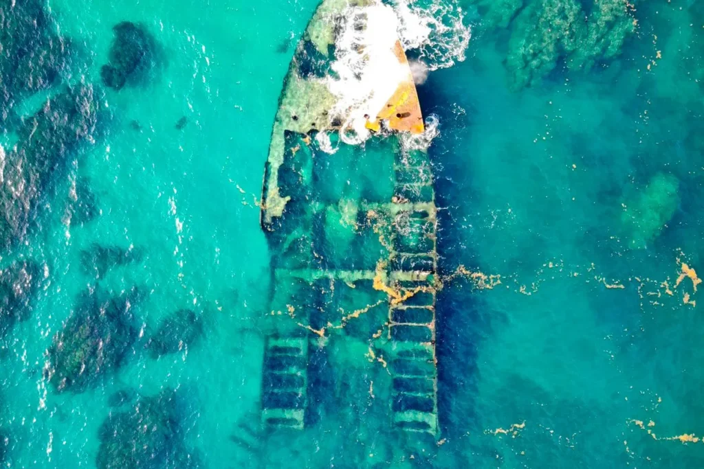 Two abandoned wooden boats wrecked on a tidal shoreline
