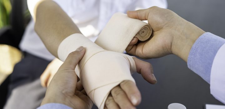 A doctor wrapping an injured patient's hand